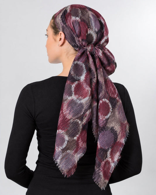 Collected NYC abstract circle print headscarf in burgundy, plum, and grey with frayed edges worn as a head wrap.