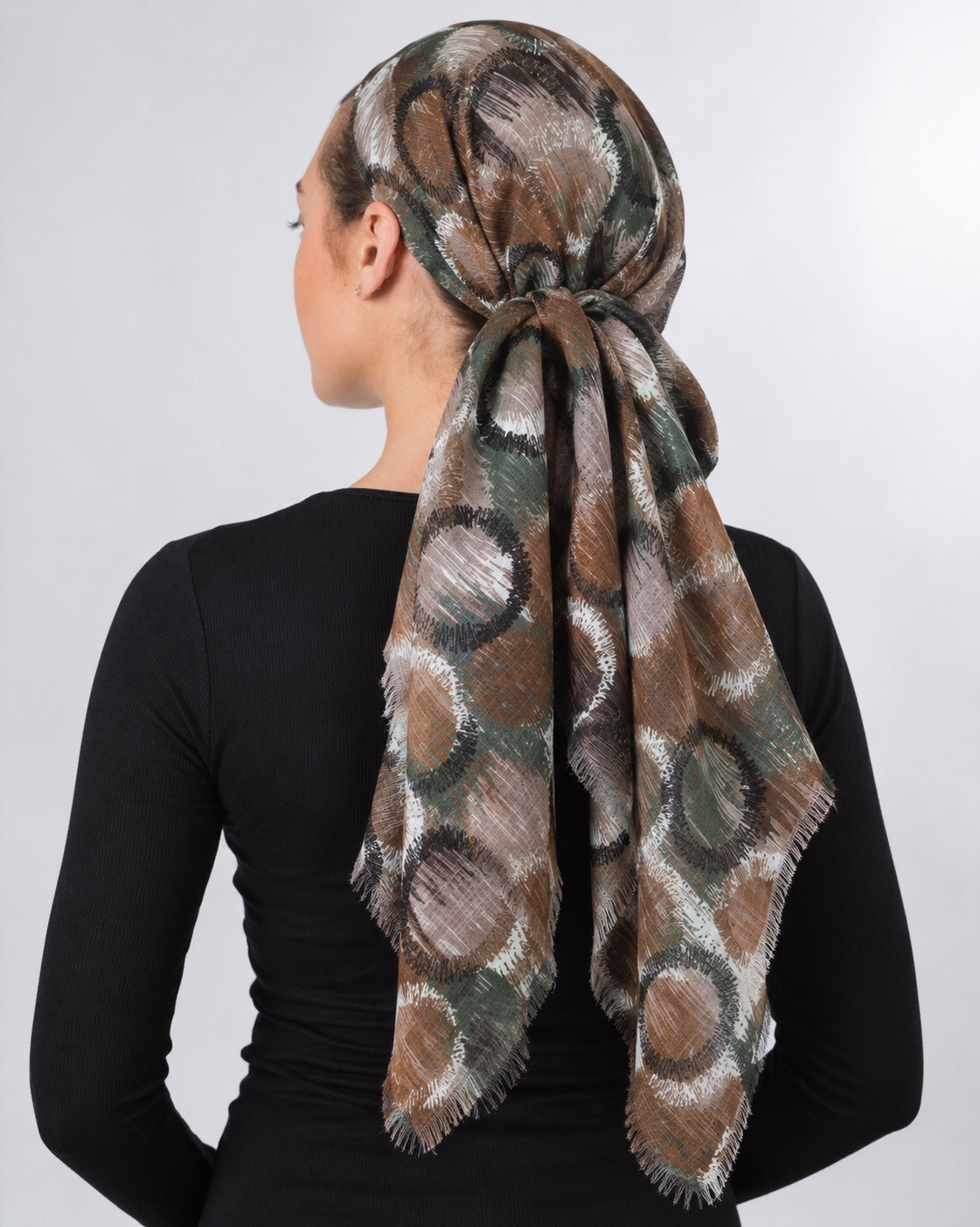 Collected NYC abstract circle print headscarf in burgundy, plum, and grey with frayed edges worn by a woman